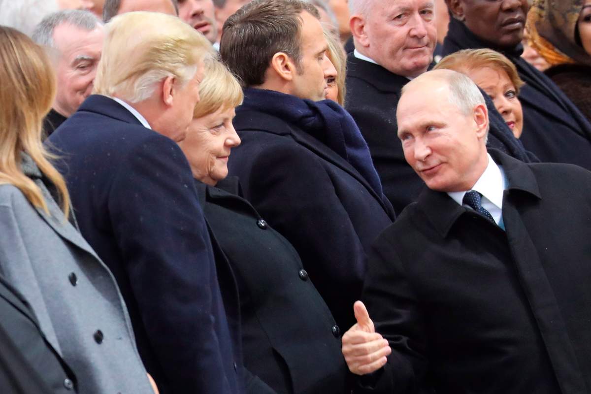 Russian President Vladimir Putin talks with German Chancellor Angela Merkel and US President Donald Trump as they attend a ceremony at the Arc de Triomphe in Paris, as part of commemorations marking the 100th anniversary of the 11 November 1918 armistice, ending World War I, Sunday, Nov. 11, 2018.