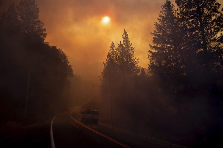 A vehicle drives through smoke from a wildfire near Pulga, Calif., Sunday, Nov. 11, 2018.
