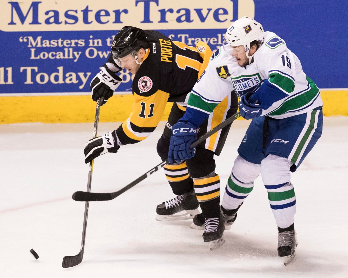 Wilkes-Barre/Scranton Penguins' Kevin Porter, left, sends the puck past Utica Comets' Cole Cassels during an AHL hockey game in Wilkes-Barre, Pa., Sunday, April 2, 2017. 