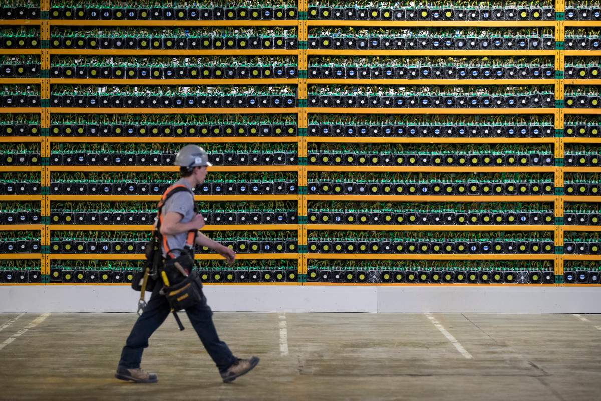 A construction worker walks past a wall of computers mining bitcoin at the Bitfarms company in Saint Hyacinthe, Quebec on Monday, March 19, 2018. THE CANADIAN PRESS IMAGES/Lars Hagberg.