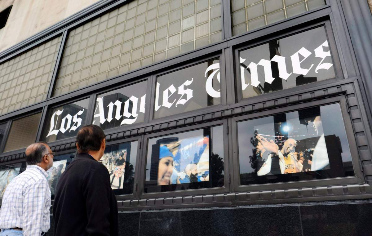 FILE - In this May 16, 2016, file photo, pedestrians look at news photos posted outside the Los Angeles Times building in downtown Los Angeles.