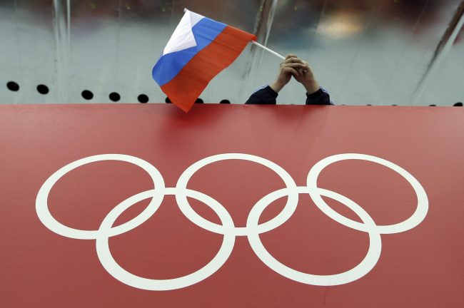 In this Feb. 18, 2014, file photo, a Russian skating fan holds the country's national flag over the Olympic rings at Adler Arena Skating Center during the 2014 Winter Olympics in Sochi, Russia. 


