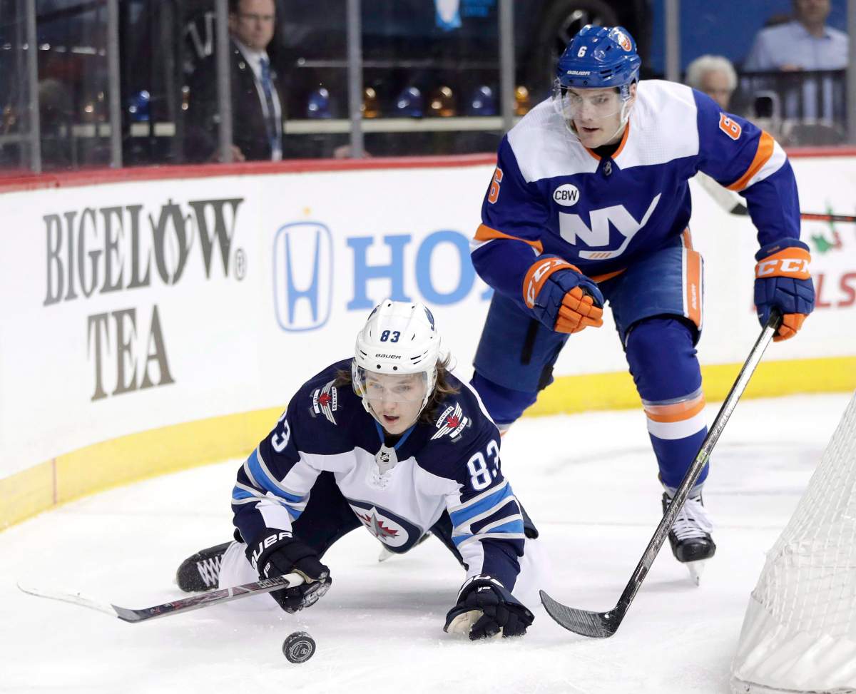 Winnipeg Jets defenseman Sami Niku, bottom, of Finland, loses his footing while trying to control the puck against New York Islanders defenseman Ryan Pulock during the first period of an NHL hockey game, Tuesday, Dec. 4, 2018, in New York. (AP Photo/Julio Cortez).