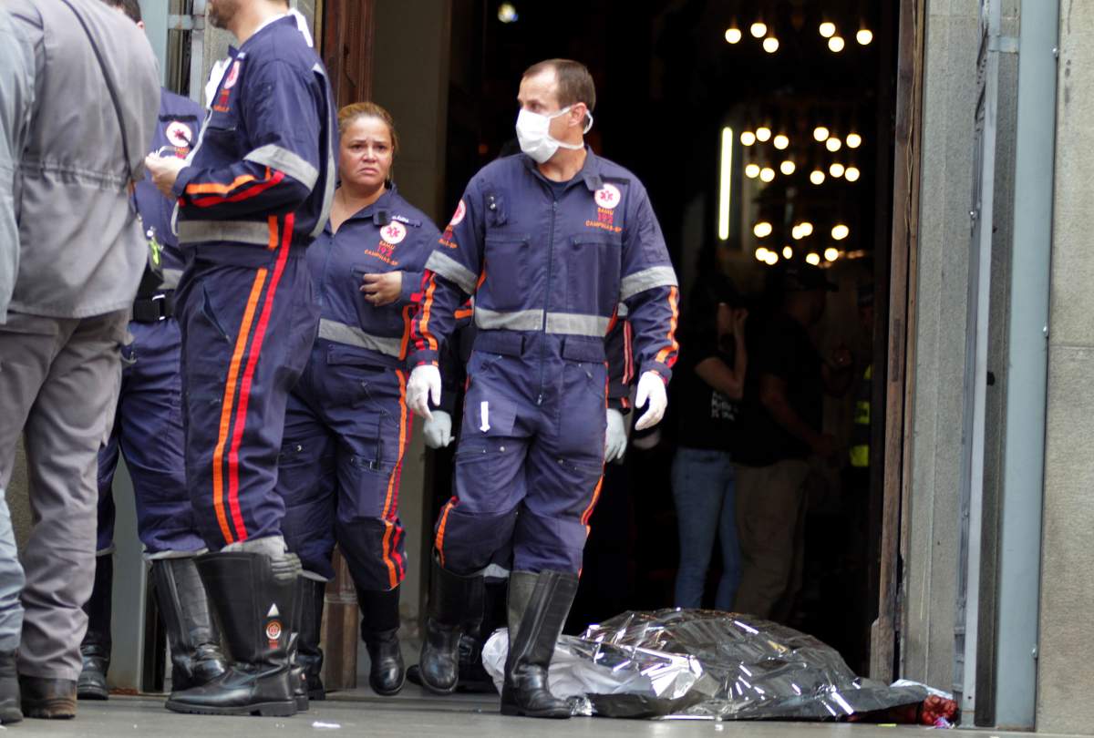 A firefighter walks next to a victim killed at the Metropolitan Cathedral in Campinas, Brazil, Tuesday, Dec. 11, 2018. Authorities say an armed man entered the cathedral in southern Brazil on Tuesday afternoon and opened fire, killing at least four people before killing himself.