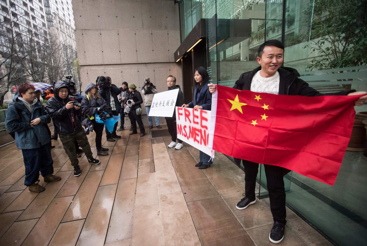 Supporters hold signs and a Chinese flag outside B.C. Supreme Court during the third day of a bail hearing for Meng Wanzhou, the chief financial officer of Huawei Technologies, in Vancouver, on Tuesday, Dec. 11, 2018. THE CANADIAN PRESS/Darryl Dyck