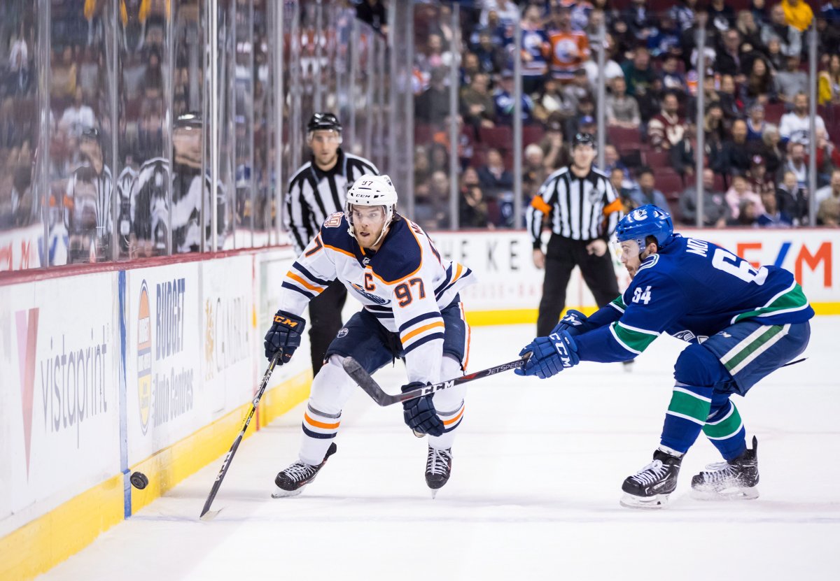 Edmonton Oilers' Connor McDavid, left, knocks the puck past Vancouver Canucks' Tyler Motte during third period NHL hockey action in Vancouver on Sunday, Dec. 16, 2018. THE CANADIAN PRESS/Darryl Dyck.