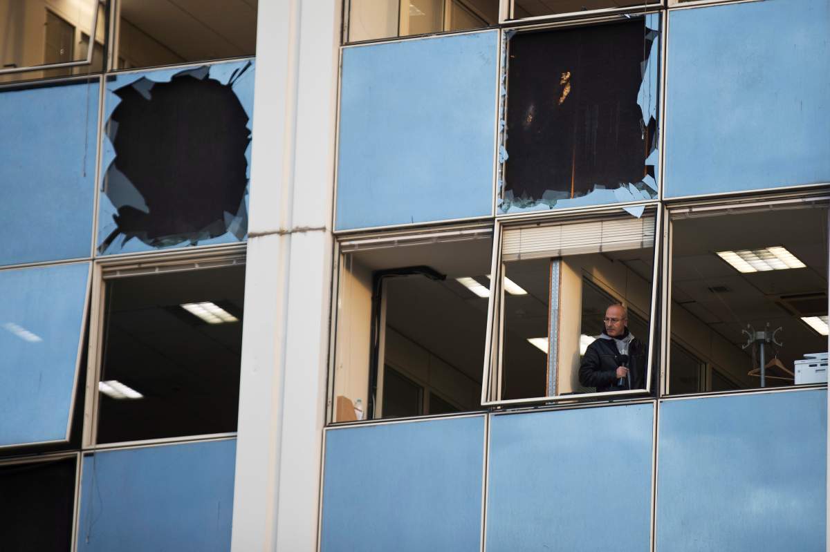 A journalist looks out a broken window after a powerful bomb exploded outside private Greek television station Skai, in Faliro, Athens, on Monday, Dec, 17, 2018.
