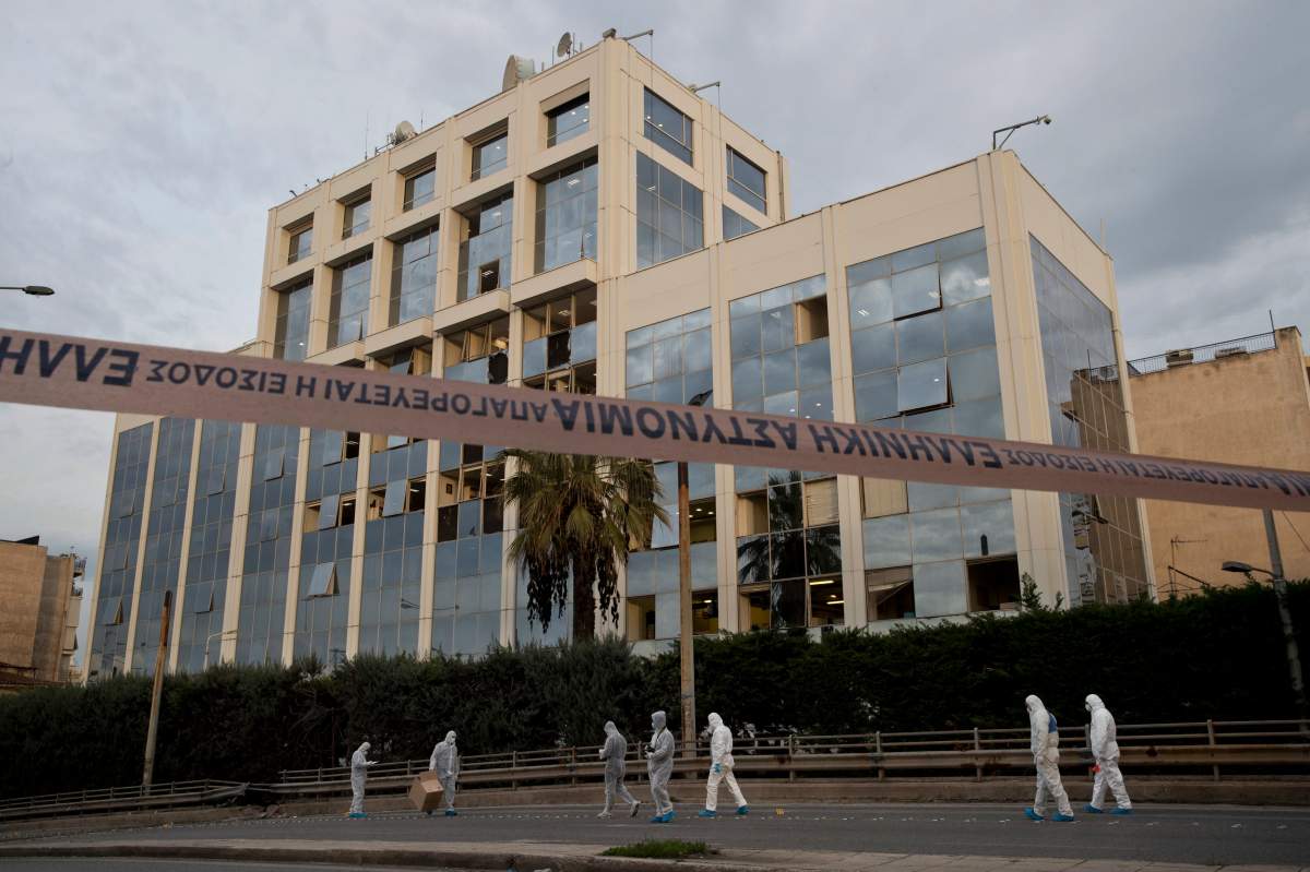 Greek forensic experts search outside the private Greek television station Skai, after a powerful bomb explosion, in Faliro, Athens.
