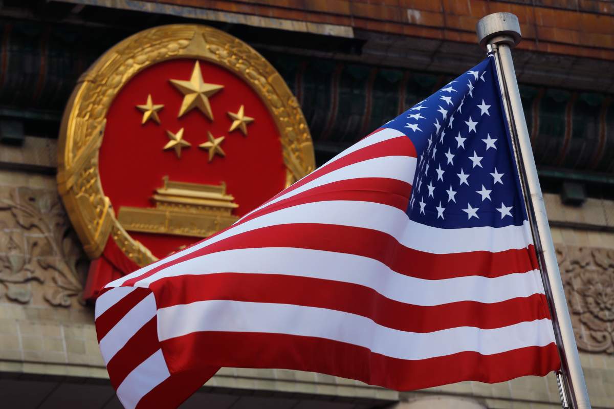 FILE - In this Nov. 9, 2017, file photo, an American flag is flown next to the Chinese national emblem during a welcome ceremony at the Great Hall of the People in Beijing.