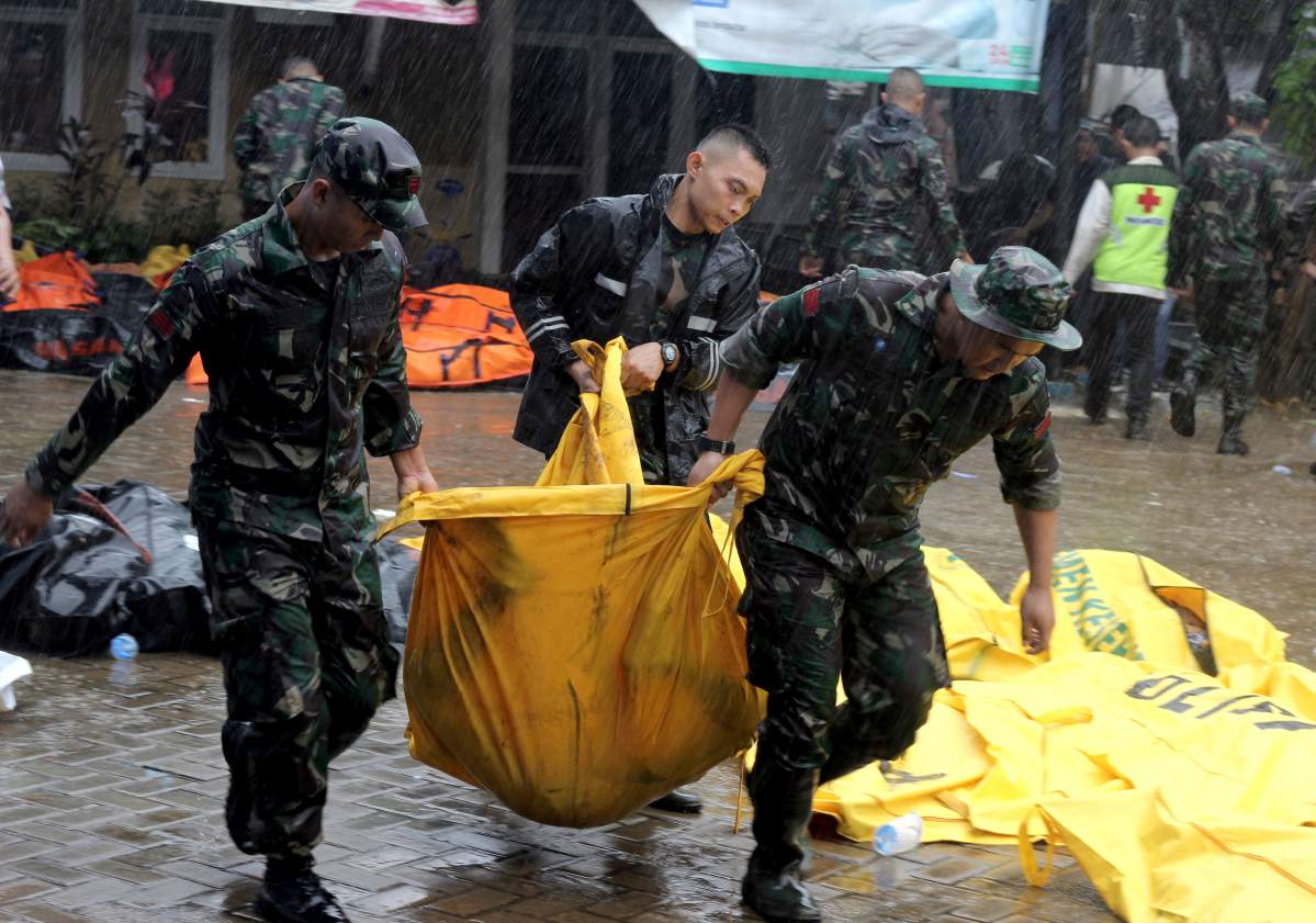 Indonesian soldiers carry a body bag containing the body of a tsunami victim, in Carita, Indonesia, Sunday, Dec. 23, 2018.