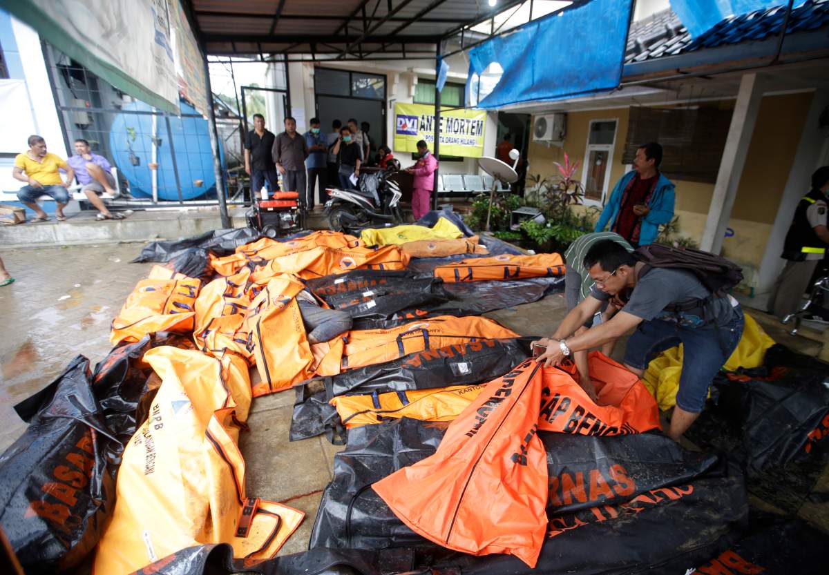 People search for relatives among the bodies of tsunami victims in Carita, Indonesia, Sunday, Dec. 23, 2018.