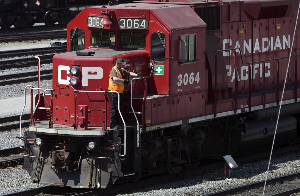 A Canadian Pacific Railway employee walks along the side of a locomotive in a marshalling yard in Calgary, Wednesday, May 16, 2012.