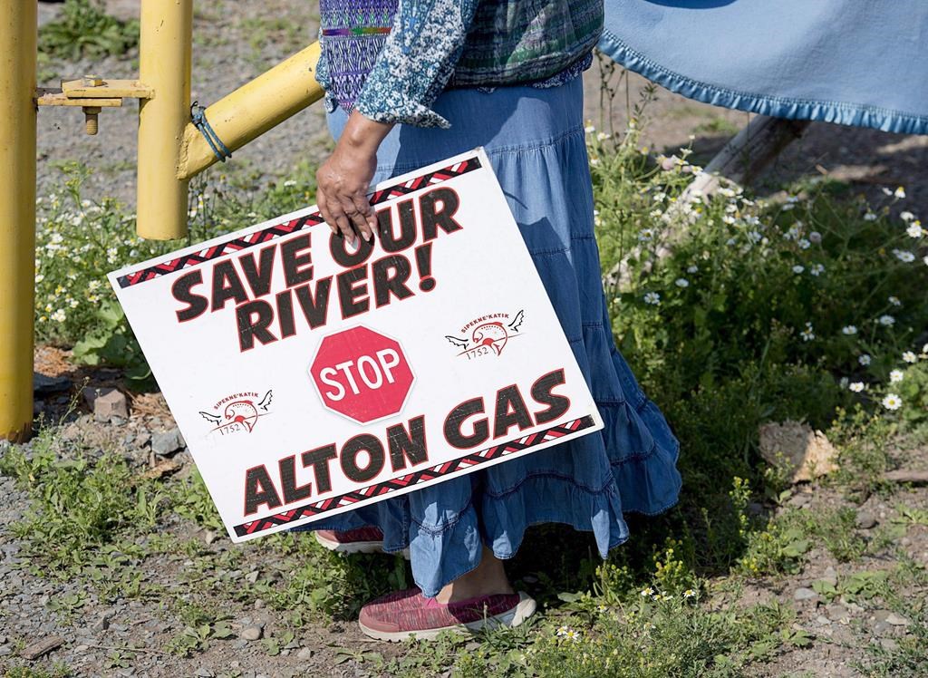 Mi'kmaq activist Ducie Howe carries a sign at an encampment near the Shubenacadie River, a 72-kilometre tidal river that cuts through the middle of Nova Scotia and flows into the Bay of Fundy, in Fort Ellis, N.S. on July 31, 2018.