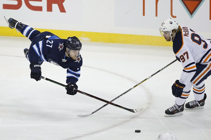 Winnipeg Jets’ Nikolaj Ehlers (27) makes a pass in front of Edmonton Oilers’ Connor McDavid (97) after he was hooked by Edmonton Oilers’ Darnell Nurse (not shown) during first-period NHL action in Winnipeg on Thursday, Dec. 13, 2018.
