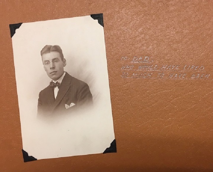 A page within the photo album, which contains a photograph of a young man dressed in a suit and a bow tie, with the caption “To: Dad, who would have like so much to have been there too.”.