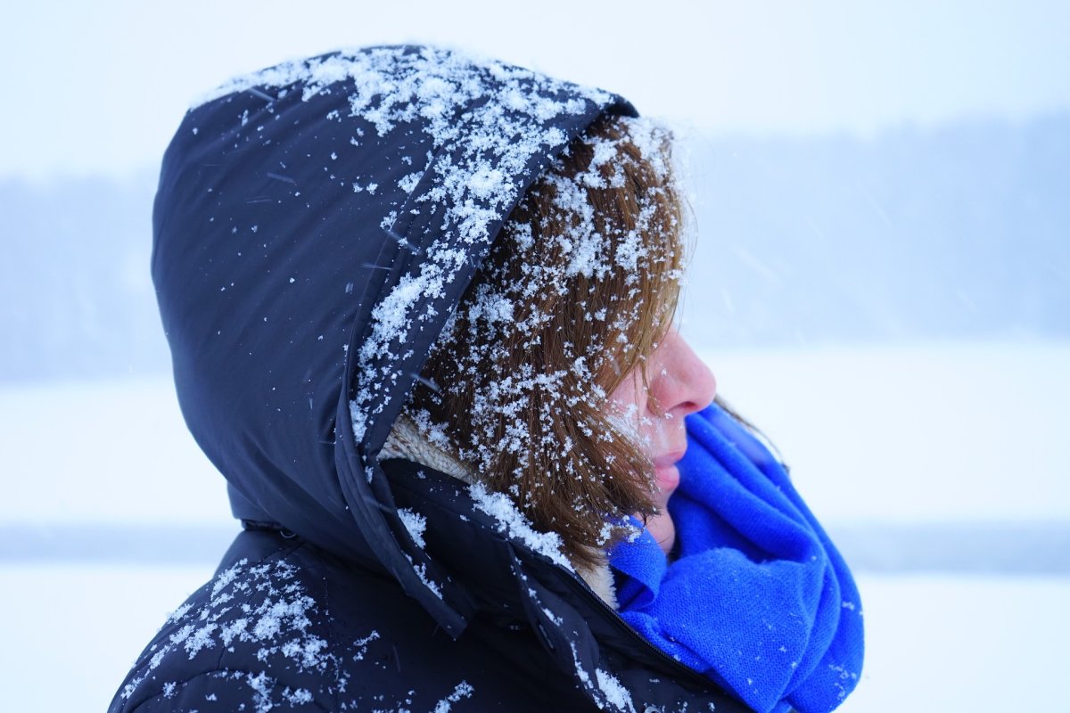 A woman shields herself on a snowy day.