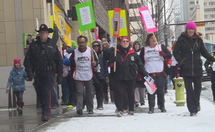 More than 150 people from different unions rallied in downtown Calgary as the snow flew on Saturday.