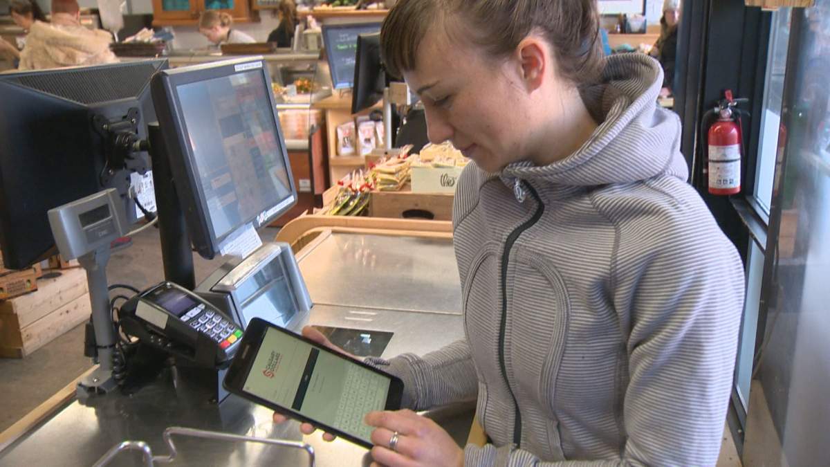 Calgary business looks at the Calgary Dollars app on her tablet.
