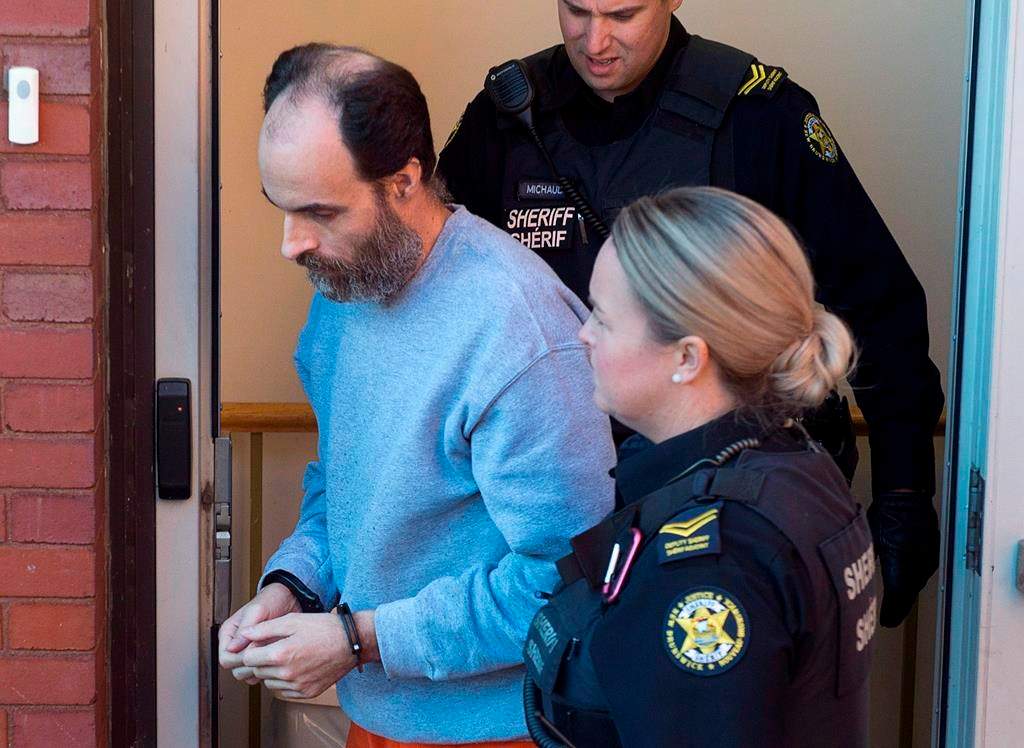 Matthew Vincent Raymond, charged with four counts of first degree murder, is escorted from provincial court in Fredericton on October 22, 2018.