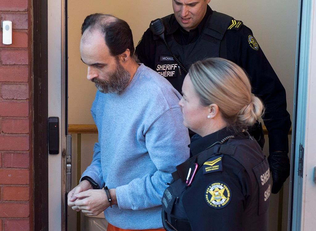 Matthew Vincent Raymond, charged with four counts of first degree murder, is escorted from provincial court in Fredericton on October 22, 2018.