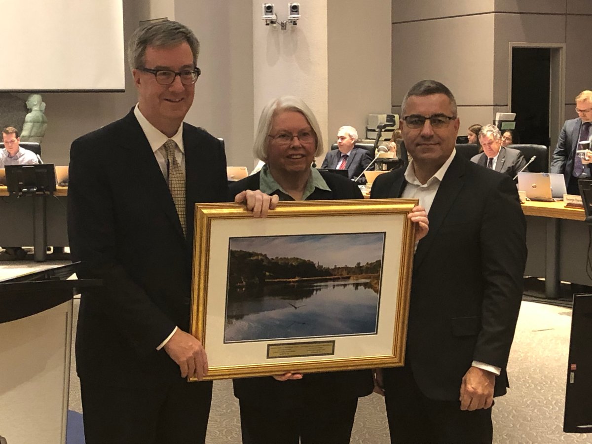 Outgoing Kanata North Councillor Marianne Wilkinson (centre) accepts a photo as a farewell gift from Mayor Jim Watson and city manager Steve Kanellakos at a ceremony before council on Nov. 28.