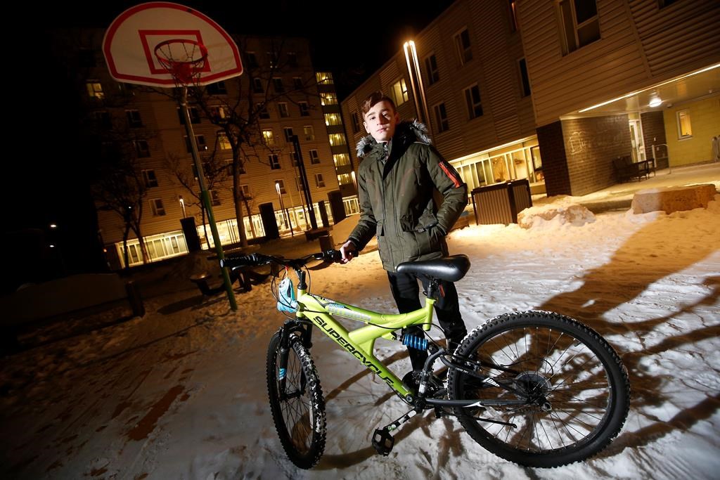 Emad Tamo, the Yazidi boy whose photo went viral after he was freed from ISIS and eventually reunited with his mother in Winnipeg, is photographed with his new bike outside his home at Immigrant and Refugee Community Organization of Manitoba (IRCOM).