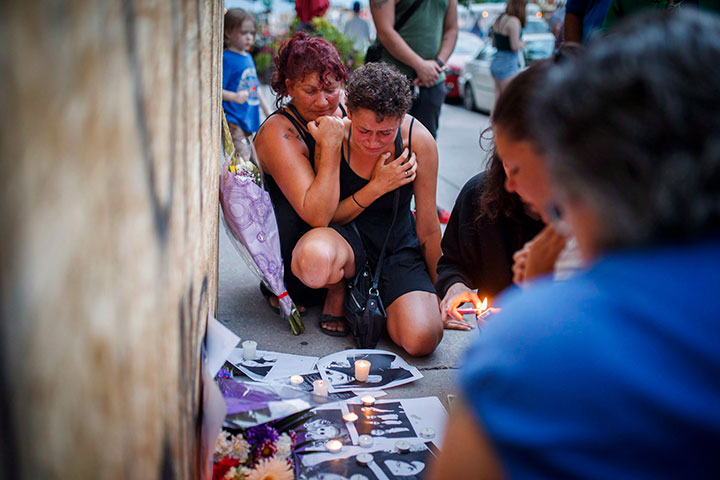 Friends of Danforth shooting victim Reese Fallon react after putting down pictures at a makeshift memorial remembering the victims of a shooting on Danforth, Ave. in Toronto on Monday, July 23, 2018.