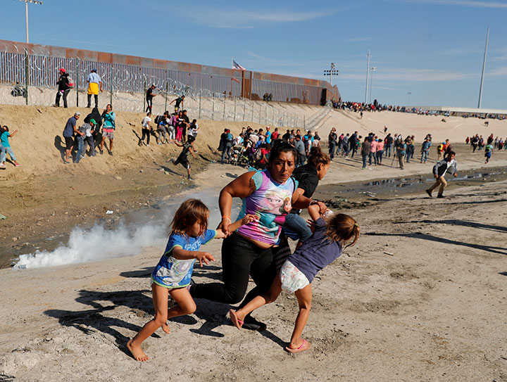 A migrant family en route to the United States runs away from tear gas in front of the border wall between the U.S and Mexico in Tijuana, Mexico, November 25, 2018.