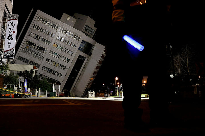 A police officer stands guard outside a damaged building after an earthquake hit Hualien, Taiwan, February 7, 2018.