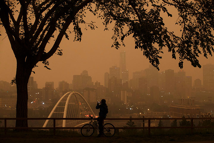 A morning commuter stops to take a photo of the city as smoke from the B.C. wildfires rolls in over Edmonton, Alta., on Wednesday August 15, 2018.