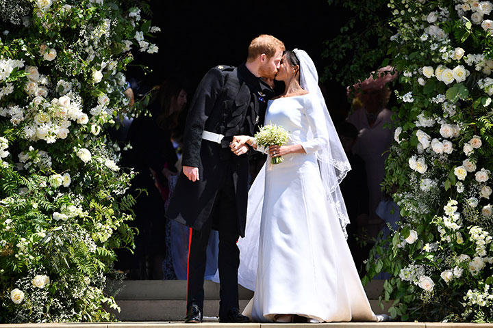 Prince Harry, Duke of Sussex kisses his wife Meghan, Duchess of Sussex as they leave from the West Door of St George’s Chapel, Windsor Castle, on May 19, 2018.
