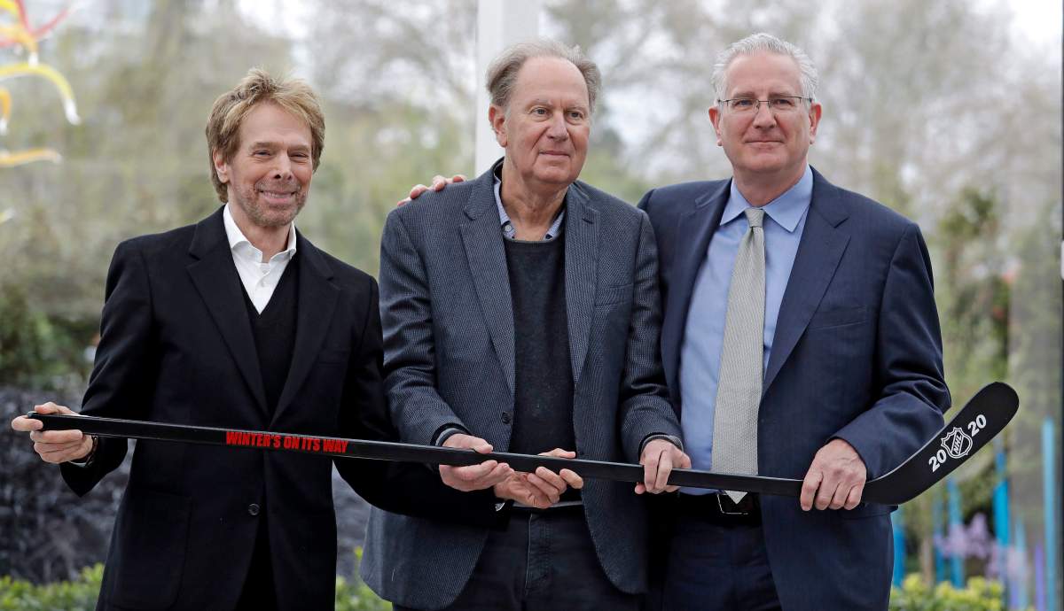 In this April 11, 2018, file photo, part-owners Jerry Bruckheimer, left, and David Bonderman pose with Tod Leiweke and a hockey stick during a news conference naming Leiweke as the president and CEO for a prospective NHL expansion team in Seattle.
