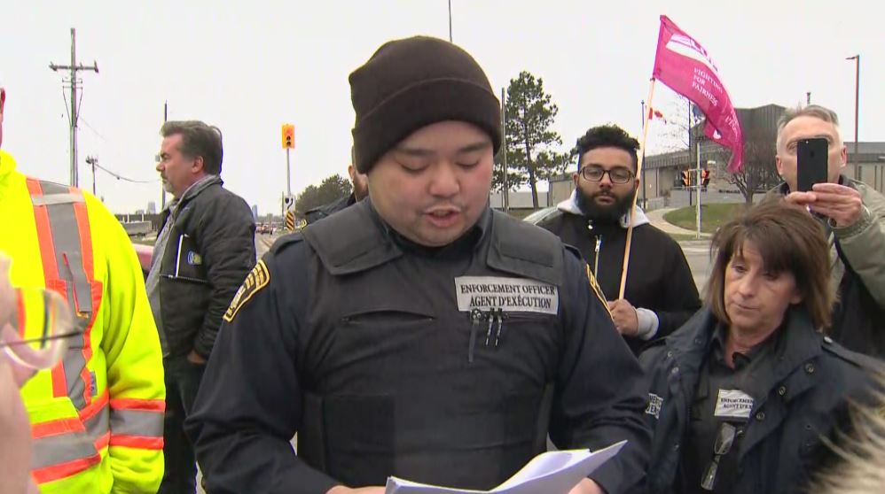 An enforcement officer reads out an injunction declaring the blocking of entrances to the facility illegal.