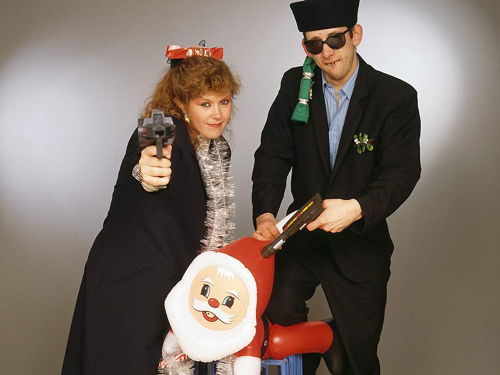 Kirsty MacColl and Shane MacGowan pose with toy guns and an inflatable Santa in a festive scenario, circa 1987.