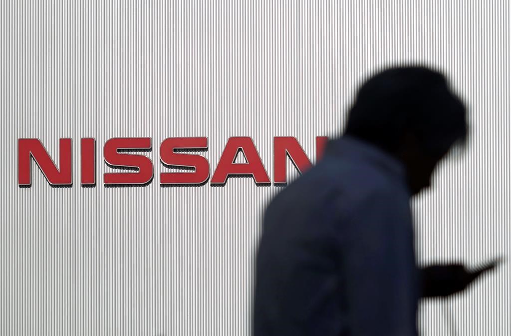 In this Nov. 21, 2018, photo, a man walks near the logo of Nissan Motor Co. at its Global Headquarters in Yokohama, near Tokyo.