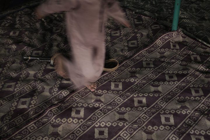 A boy steps over an AK-47 assault rifle at a camp for displaced persons, in Marib, Yemen, in this July 27, 2018, photo.