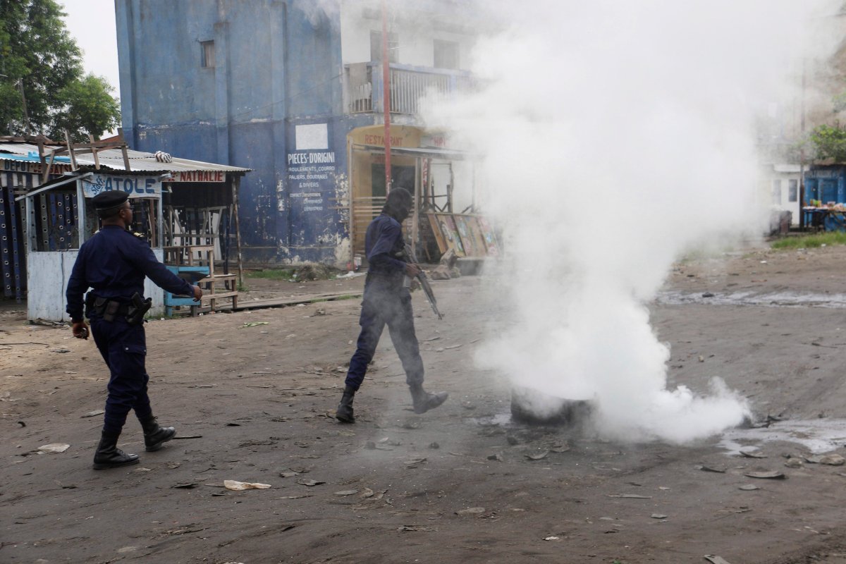 Policemen walk past burning debris during protests in Kinshasa, Democratic Republic of Congo, Sunday, Dec. 31, 2017.