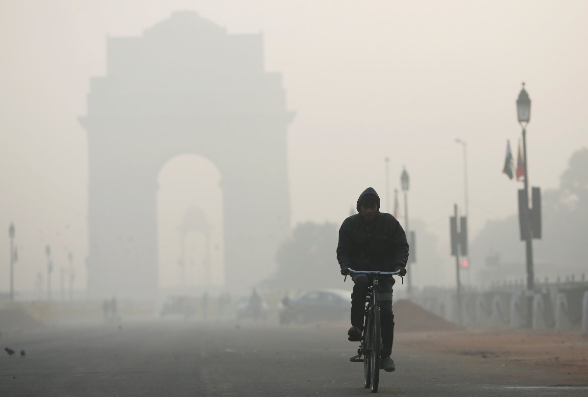 A man rides his bicycle in front of the India Gate shrouded in smog in New Delhi, India, .