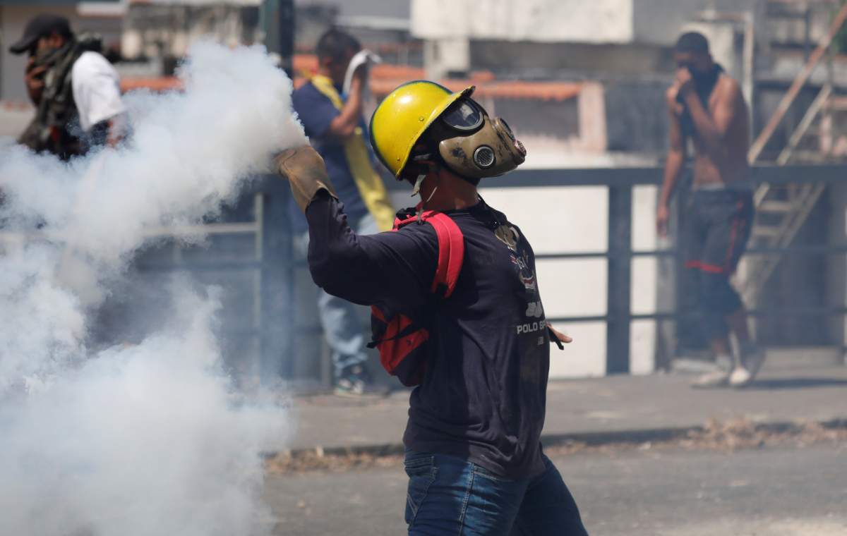 A demonstrator throws back a tear gas canister during a protest against Venezuelan President Nicolas Maduro’s government in Caracas, Venezuela January 23, 2019.