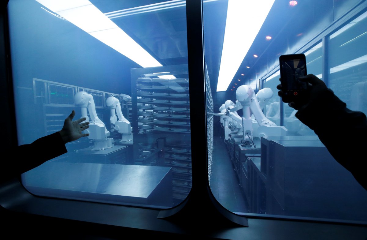 A customer takes a picture as robotic arms collect pre-packaged dishes from a cold storage, done according to the diners' orders, at Haidilao's new artificial intelligence hotpot restaurant in Beijing, China.