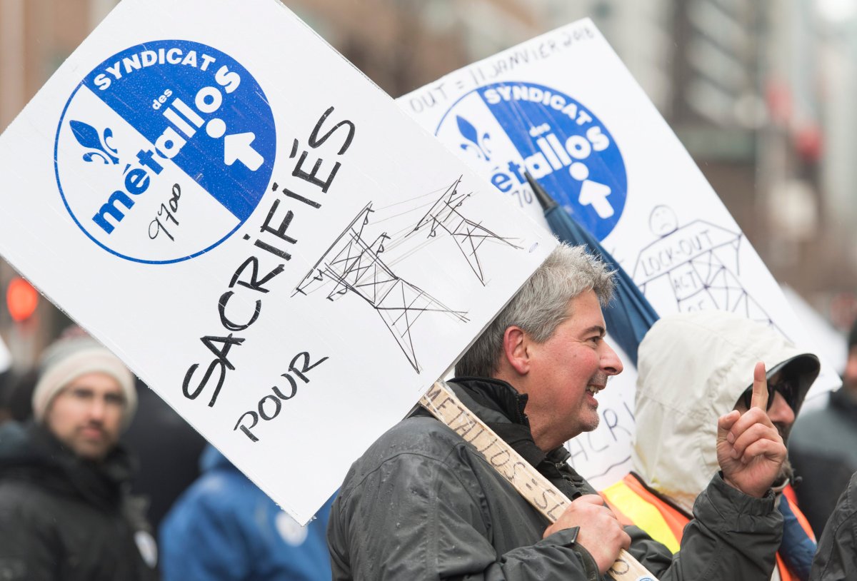 Members of Steelworker Unions hold up signs during a protest in Montreal. They are demonstrating against a lockout of workers at an Alcoa smelter plant in Bécancour, Que.