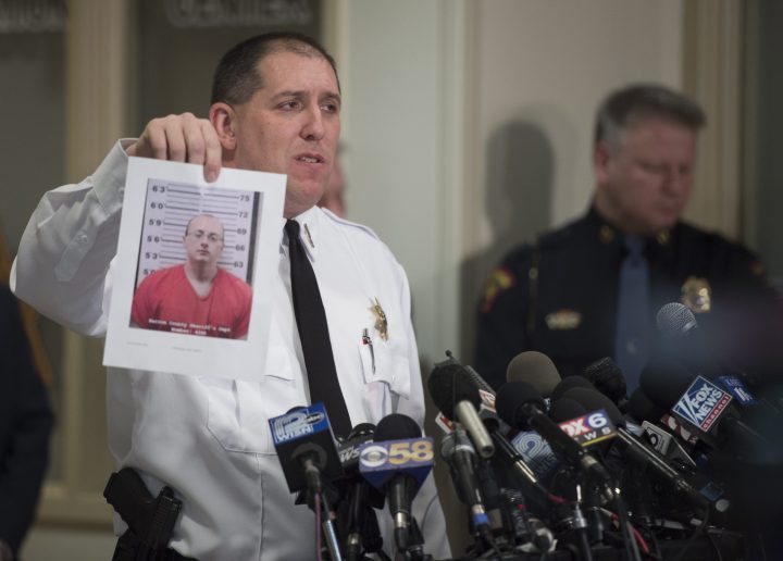 Baron County Sheriff Chris Fitzgerald holds up a photo of the suspect, Jake Thomas Patterson, as he announces that Jayme Closs was found alive.