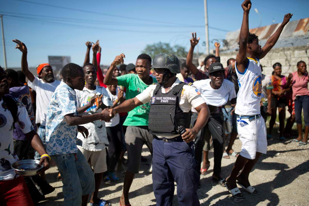 In this Dec. 10, 2018, photo, a resident shakes hands with police inspector Seraphin Frantz after police arrested an alleged gang member whom residents identify as one of the perpetrators of the massacre in the La Saline slum of Port-au-Prince, Haiti.
