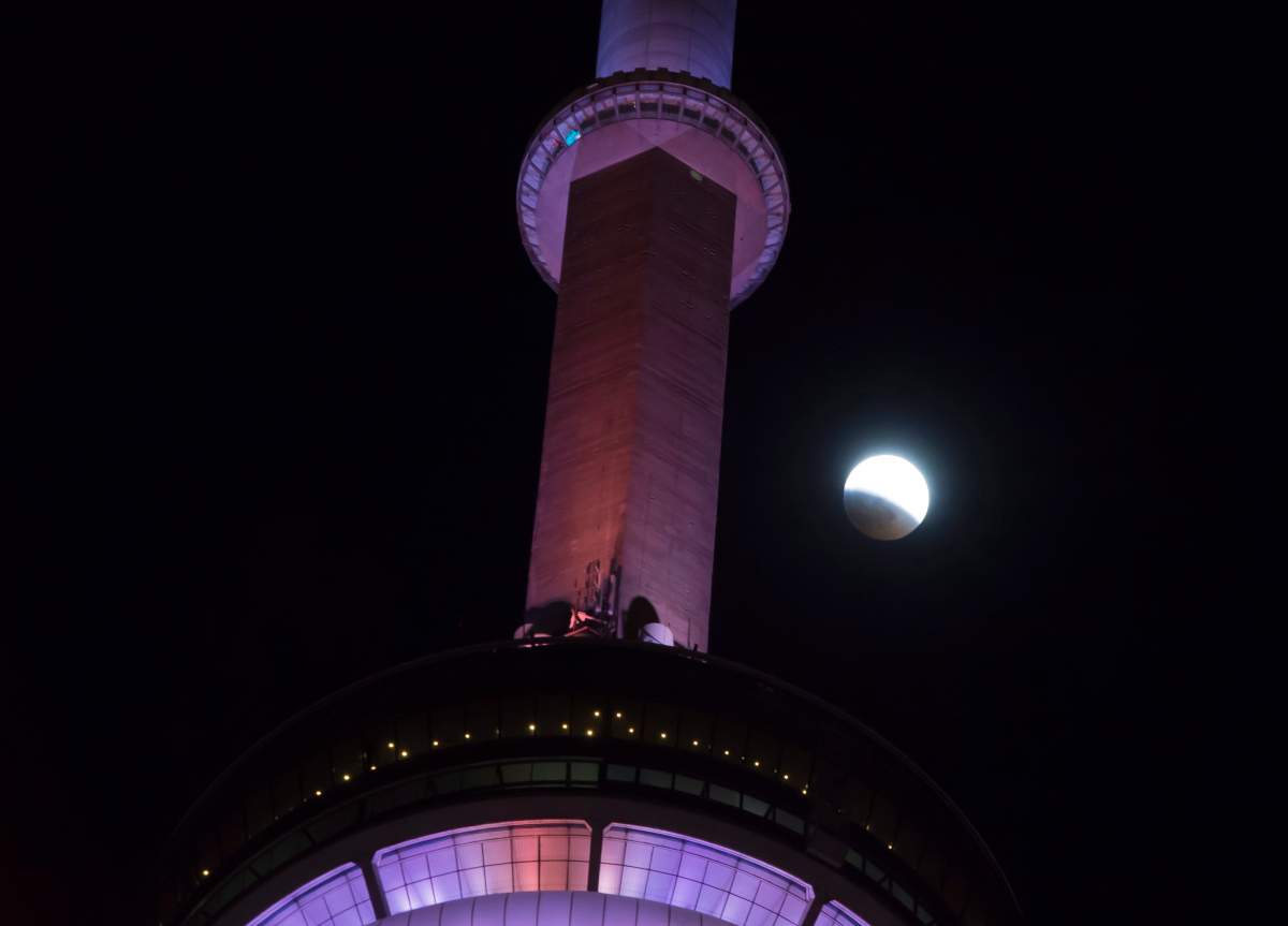 An eclipse of the moon progresses behind the CN Tower in Toronto on Sunday, Jan. 20, 2019.