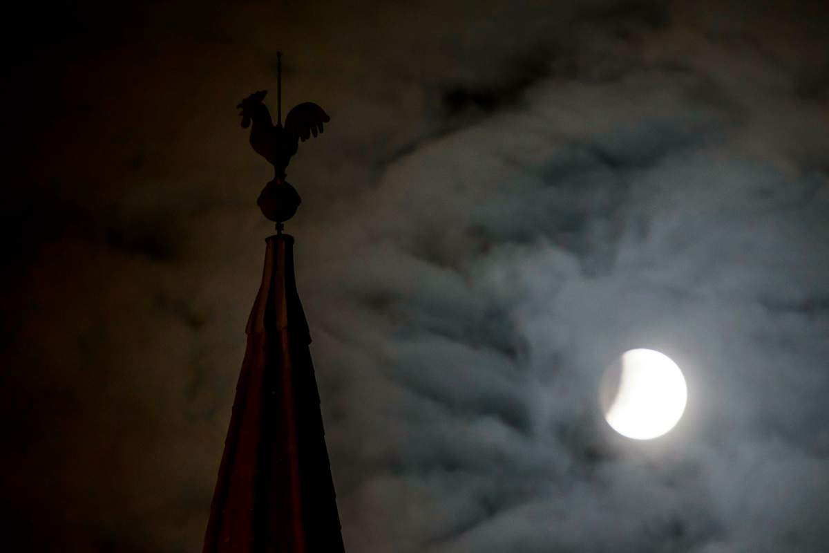 The moon fully shadowed by the Earth is seen next to a steeple during a total lunar eclipse in Salgotarjan, 109 km northeast of Budapest, Hungary, early Monday, Jan. 21, 2019.