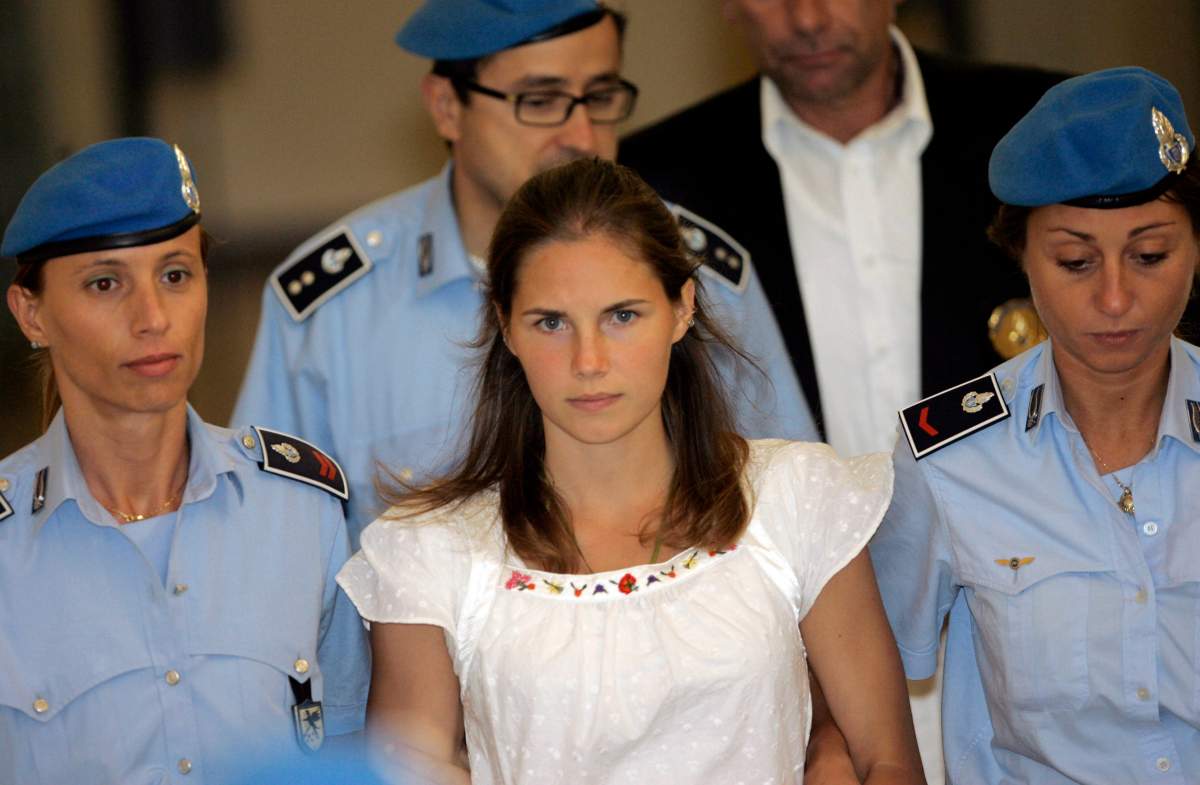 FILE - In this Tuesday Sept. 16, 2008 file photo, American murder suspect Amanda Knox, center, is escorted by Italian penitentiary police officers from Perugia's court after a hearing, central Italy.  Europe's human rights court has ordered Italy to pay Amanda Knox around 18,000 euros ($20,000) in financial damages for police failure to provide legal assistance and a translator during questioning following the Nov. 1, 2007 killing of her British roommate. The European Human Rights Court in Strasbourg, France, on Thursday ruled that Italy must pay Knox 10,400 euros damages plus 8,000 euros for costs and expenses. 
