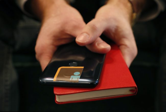 John Scott-Railton, a senior researcher at the Citizen Lab, holds his cell phone which has its camera blocked by an adhesive sticker, as he poses for a photograph, Jan. 17, 2019, in New York. 

