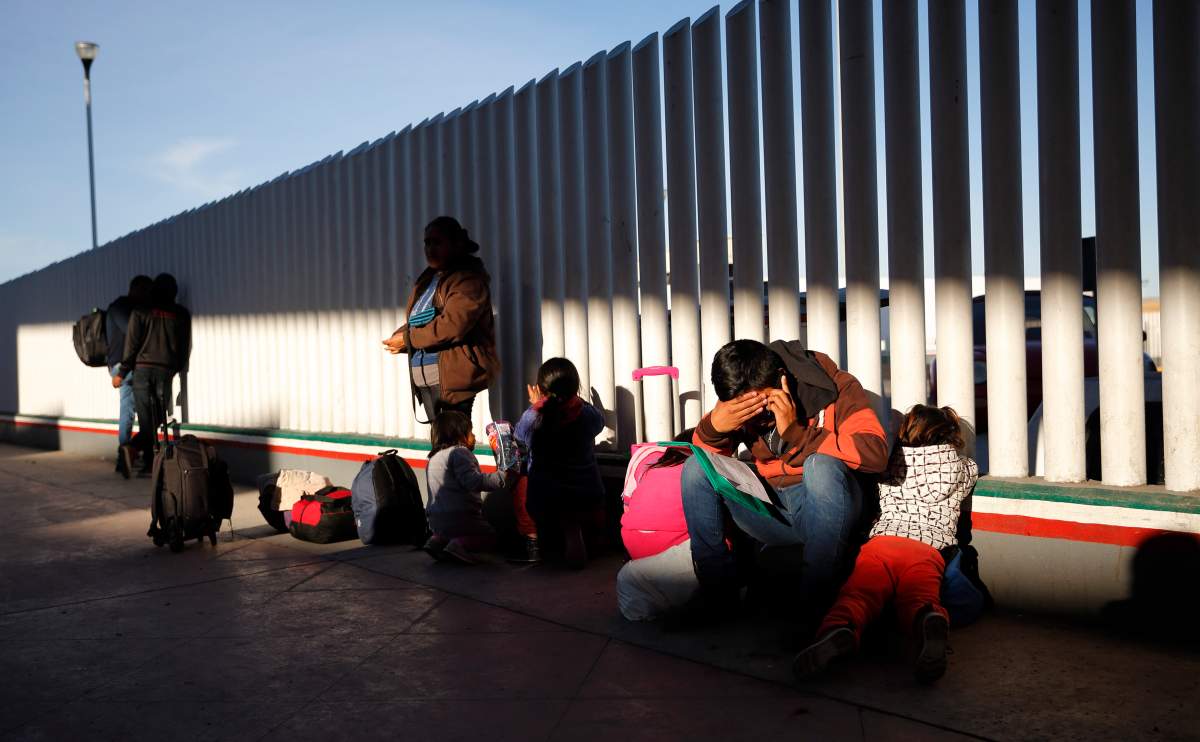A migrant sits with his children as they wait to hear if their number is called to apply for asylum in the United States, at the border, Friday, Jan. 25, 2019, in Tijuana, Mexico. 