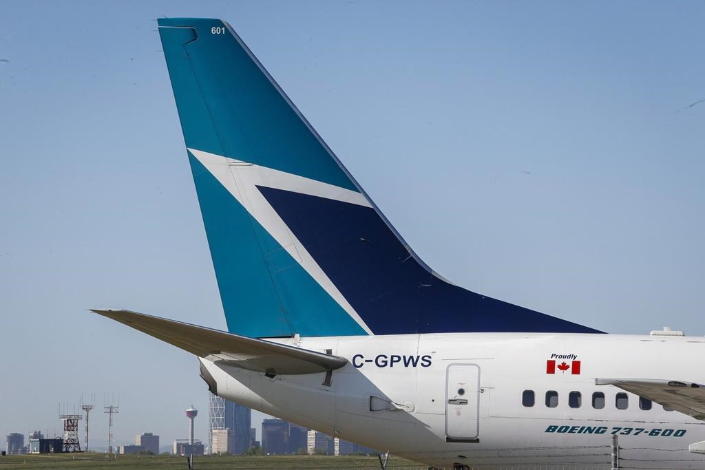 The tail of a WestJet plane is seen dwarfing the Calgary skyline before the airline's annual meeting in Calgary, Tuesday, May 3, 2016.