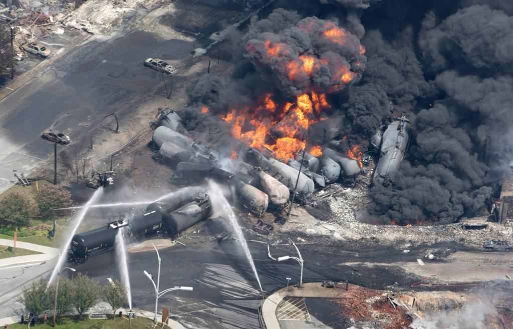 Smoke rises from railway cars that were carrying crude oil after derailing in downtown Lac-Megantic, Que., Saturday, July 6, 2013. Canadian members of Parliament have passed a unanimous motion condemning Netflix for using images of the Lac-Megantic rail disaster in fictional dramas and are demanding financial compensation for the Quebec community for using the tragic images without consent.